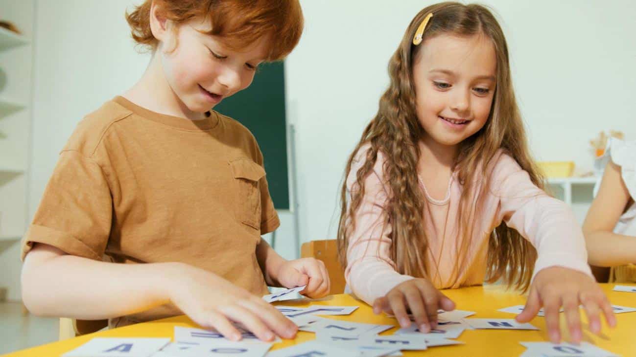 Two kids play with small alphabet flash cards for toddlers
