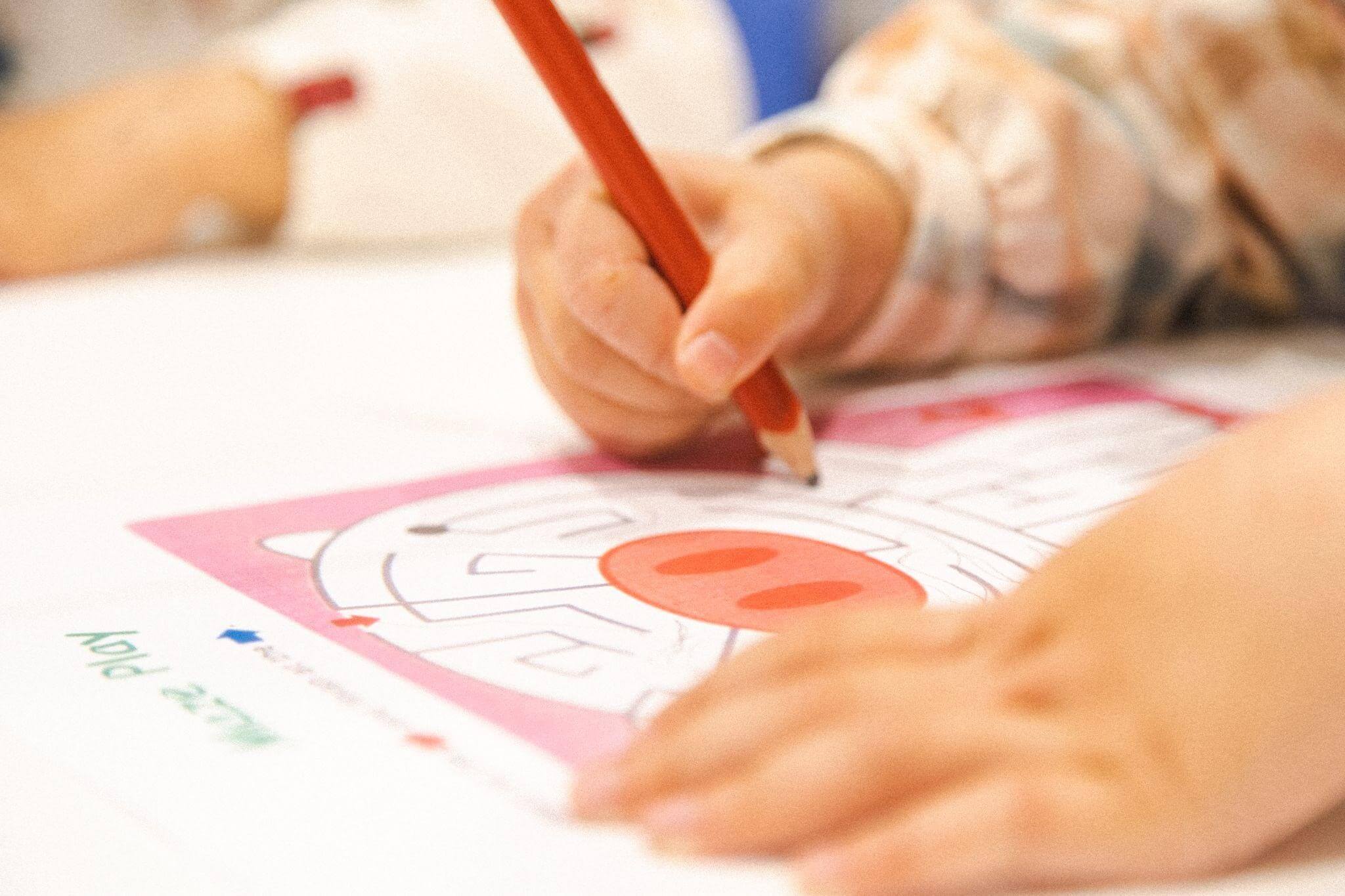 A young child's hand is holding a pencil as she completed a maze in a Shichida class