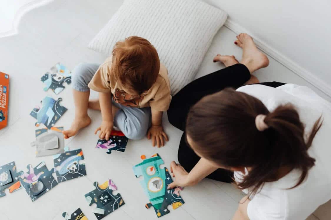 A toddler completing a puzzle with his mum