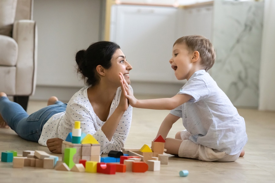 Building blocks together is an example of maths games your kid will love, here a mum and her preschooler build wooden blocks together in their home.