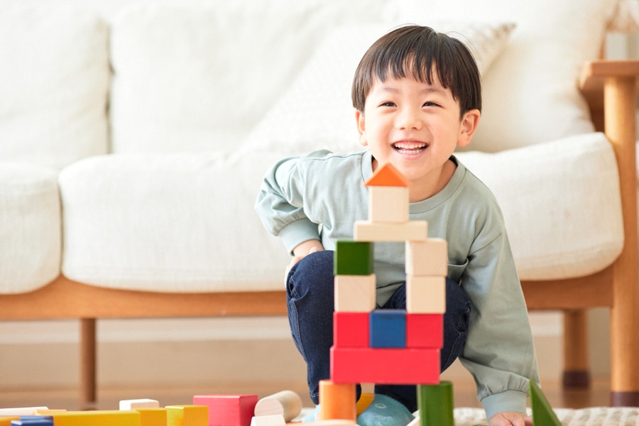 Goal Setting For Kids, featuring a preschool child building a block tower, with a big smile!