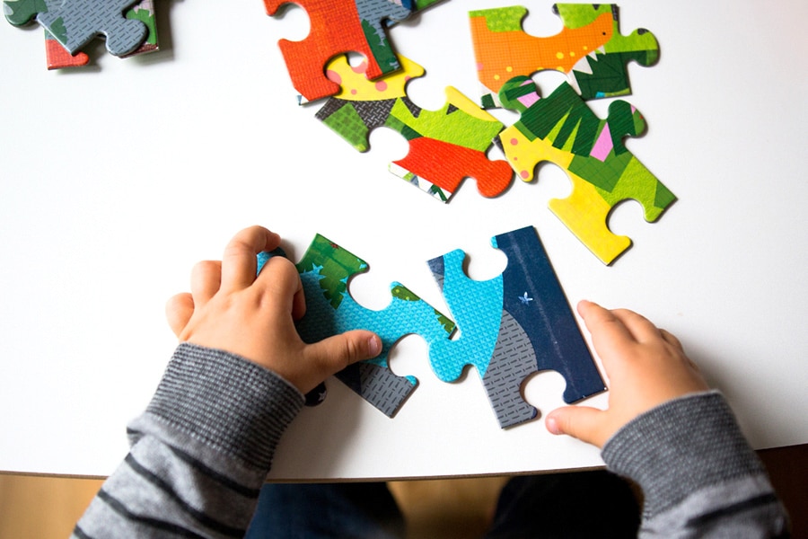 Benefits of puzzles for toddlers, featuring a preschooler building a puzzle.