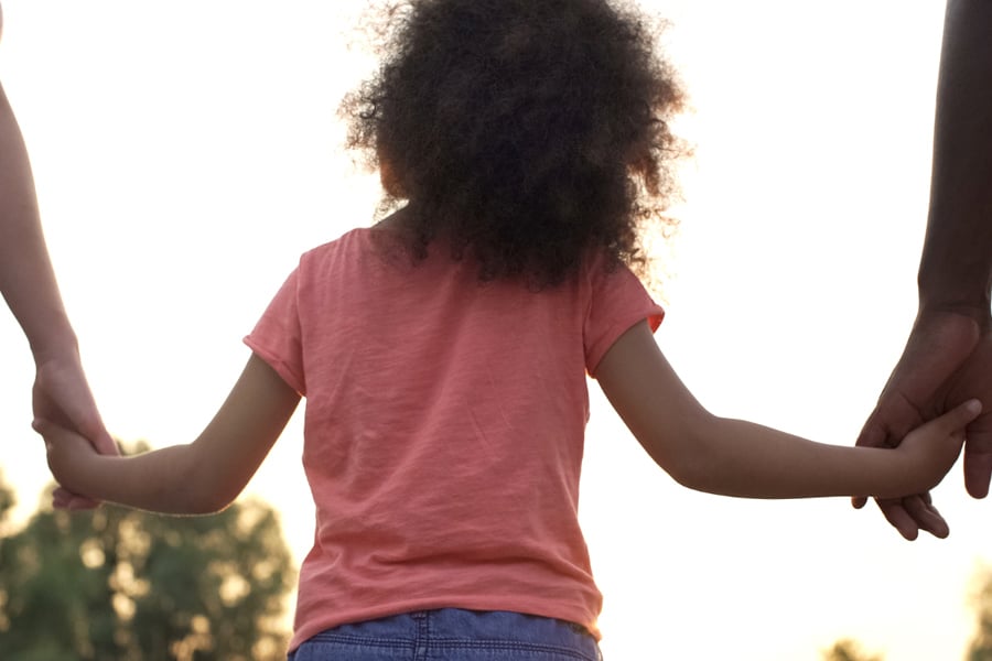 Parenting styles that encourage quality time spent together reaps big rewards for kids in their future. Here a preschool walks outside, holding hands with 2 adults.