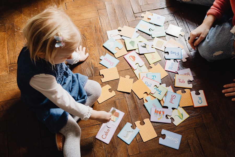 Two preschoolers playing a word game for kids, on the floor.