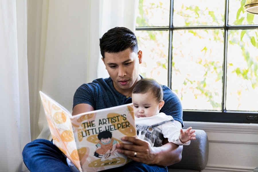 Benefits of reading for kids, here a dad reads to his baby.