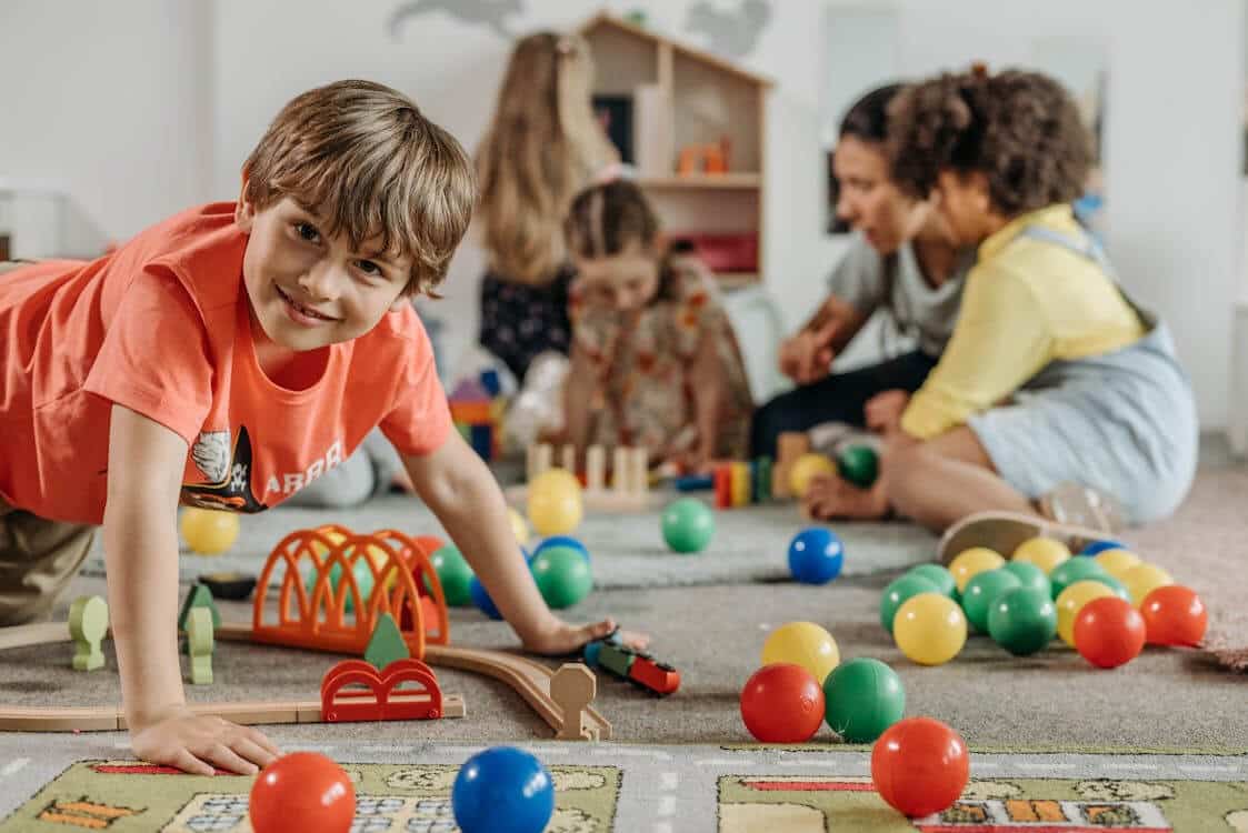 Spatial awareness development through games, here a preschooler is playing with colourful toys on the floor