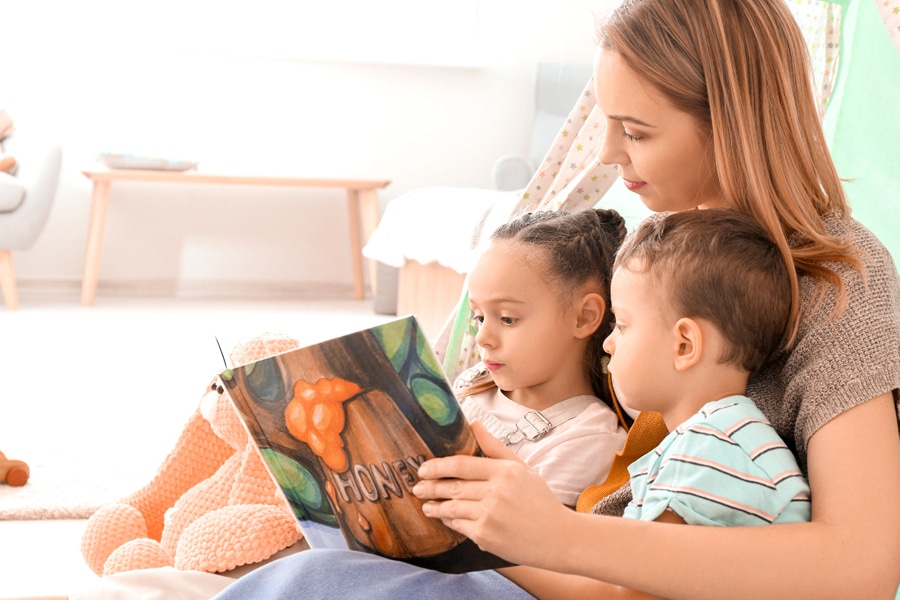 A mum reading at home with her two young toddlers.