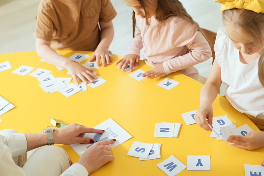 Word games for kids, featuring preschoolers playing with letter cards at a table
