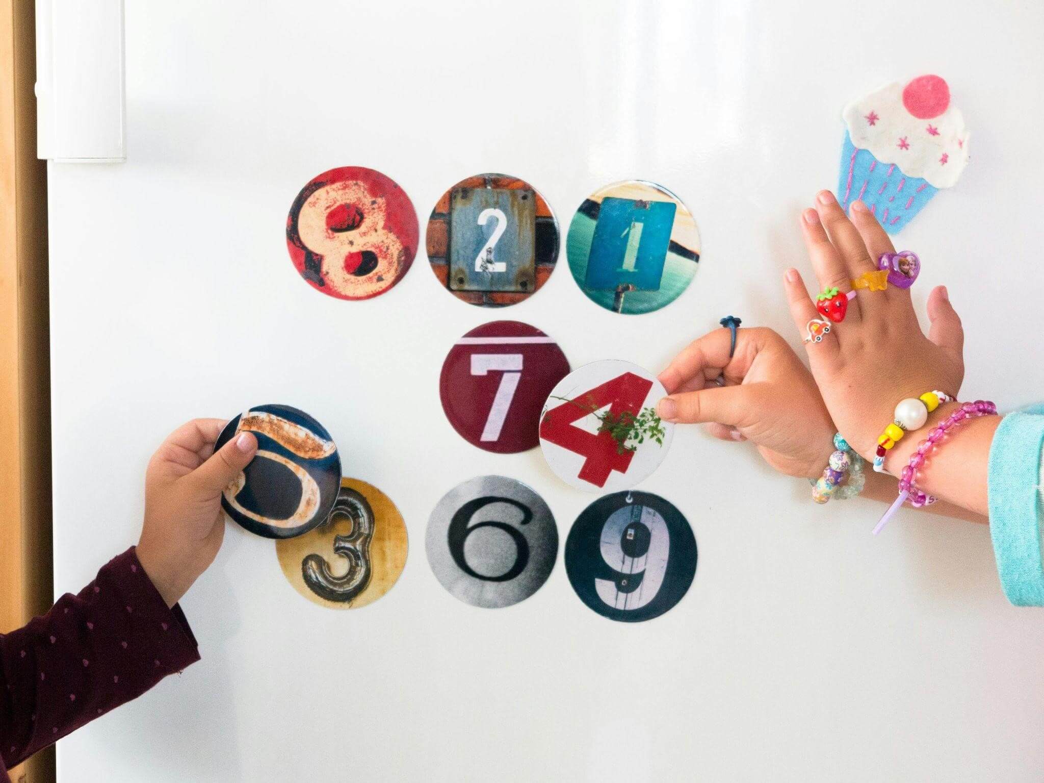 Two children are joyfully playing with activities to improve numeracy skills, colorful number magnets on a refrigerator, creating number sequences together